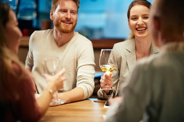 Amigos caucasianos alegres sentados no restaurante, bebendo vinho e passando tempo de qualidade juntos. Reunião . — Fotografia de Stock