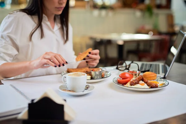 Close-up van aantrekkelijke hongerige brunette met franse toast voor het ontbijt tijdens het zitten in restaurant. — Stockfoto