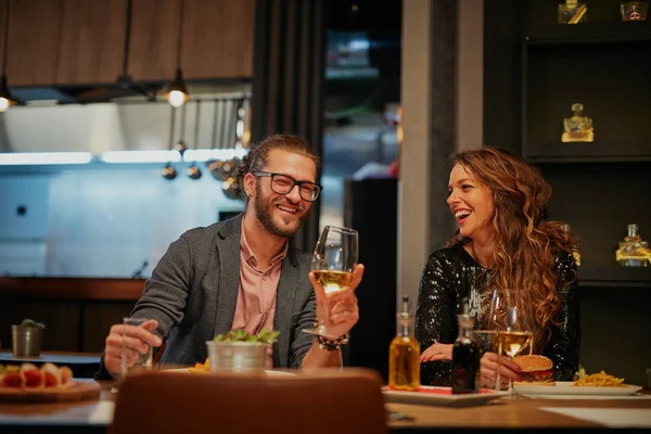Vonzó kaukázusi pár szerelmes ül az étteremben, bort iszik, mosolyog és flörtöl. — Stock Fotó