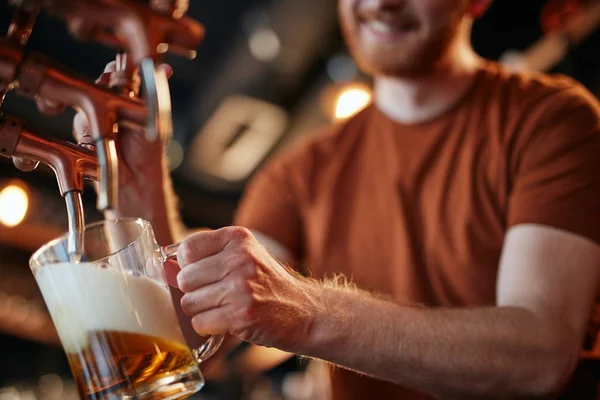 Крупним планом кавказький імбирний бармен кидає пиво в пабі . — стокове фото