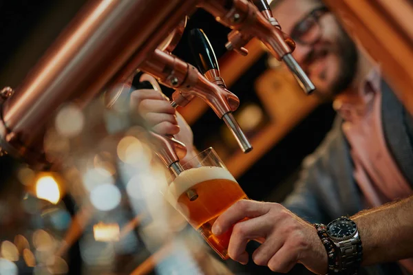 Nahaufnahme eines gutaussehenden kaukasischen Barkeepers mit Bart, der in der Bar steht und Bier aus dem Zapfhahn gießt. — Stockfoto