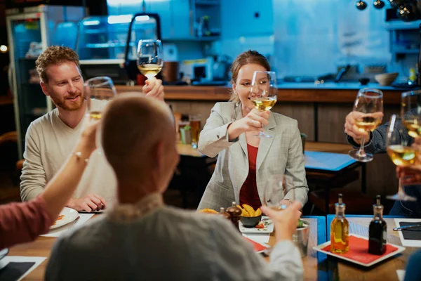 Skupina nejlepších přátel sedících v restauraci na večeři a pronášejících přípitek s vínem. — Stock fotografie