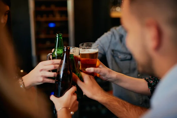 Close up de pequeno grupo de amigos em pé no pub e fazer um brinde com cerveja . — Fotografia de Stock