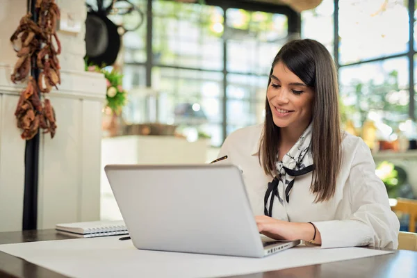 Aantrekkelijke zakenvrouw die in een café zit en laptop gebruikt. Op tafel liggen laptop, notitieboekje en kopje koffie. Handen op het toetsenbord. — Stockfoto
