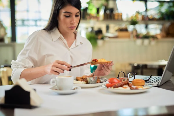 Mooie vrouw die wentelteefjes eet als ontbijt terwijl ze in restaurant zit. — Stockfoto
