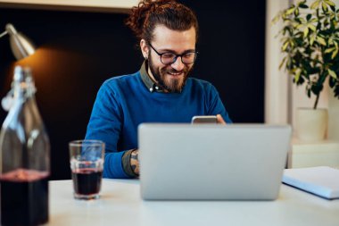 Çekici beyaz sakallı girişimci ofisinde oturuyor, akıllı telefon kullanıyor ve işe ara veriyor..