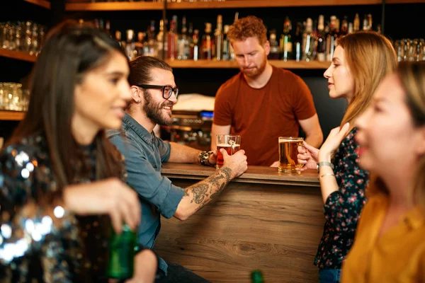 Grupo de amigos bebiendo cerveza, charlando y divirtiéndose en el pub. Noche fuera. . — Foto de Stock