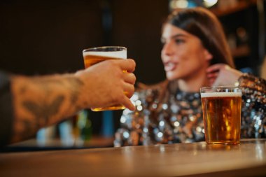 Bar tezgahının yanında oturan, bira içen ve flört eden bir çift..