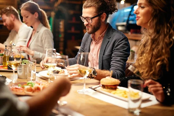 Skupina nejlepších přátel sedí v restauraci, večeří, popíjí víno a baví. — Stock fotografie