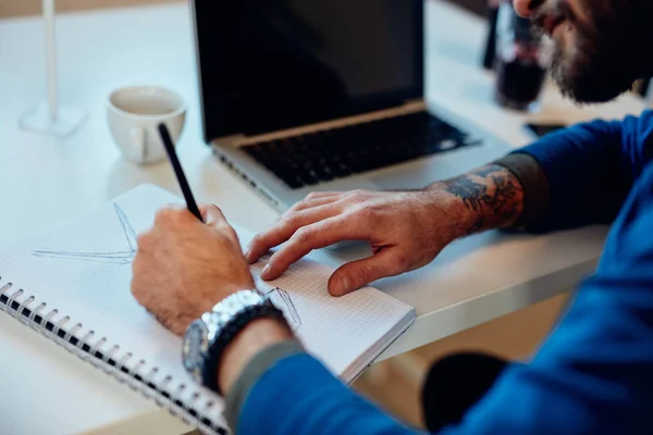 Close up of dedicated innovative caucasian engineer sitting in his office and drawing windmill. Sustainable development concept. — Stock Photo, Image