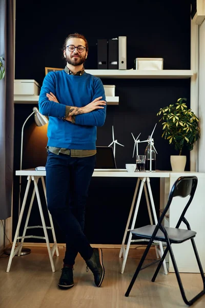 Longitud completa de guapo ingeniero caucásico de moda de confianza en sí mismo de pie en su oficina y mirando a la cámara. Concepto de desarrollo sostenible . — Foto de Stock