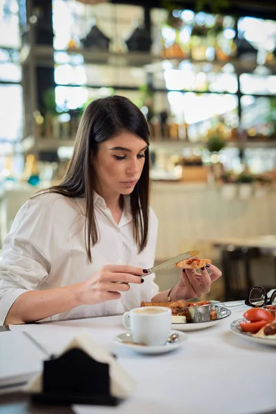 Mooie vrouw die wentelteefjes eet als ontbijt terwijl ze in restaurant zit. — Stockfoto
