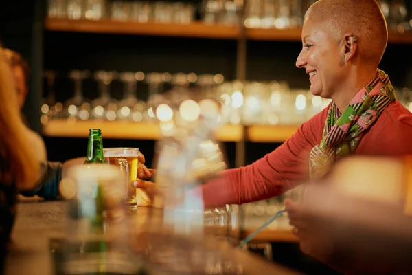 Lächelnde Seniorin steht in Kneipe und serviert Kunden Bier. — Stockfoto