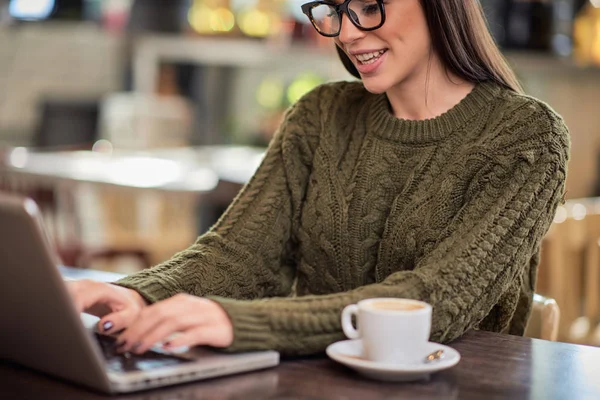 Nádherný úsměv zaměřený žena na volné noze sedí v kavárně a pomocí notebooku do práce. — Stock fotografie