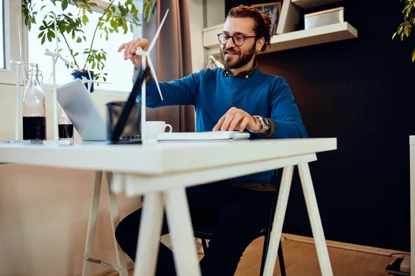 Knappe blanke ondernemer met een baard die in zijn kantoor zit en aan een belangrijk project werkt. Duurzaam concept. — Stockfoto