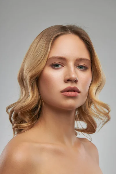 Prachtige Kaukasische blonde vrouw met make-up poseren in de studio en kijken naar de camera. — Stockfoto