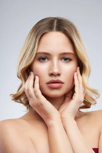 Wunderschöne kaukasische blonde Frau mit Make-up posiert im Studio und schaut in die Kamera. — Stockfoto