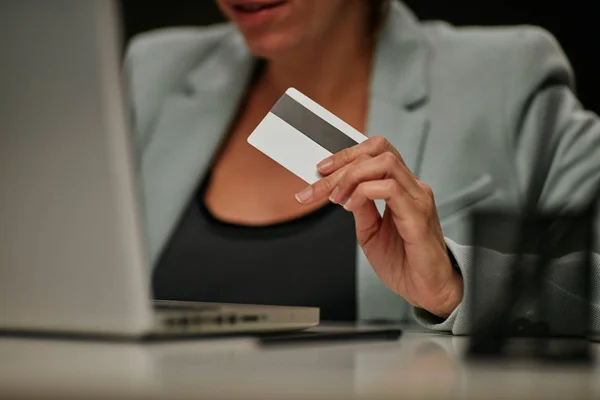Giovane donna d'affari caucasica seduta nel suo ufficio e che utilizza la carta di credito per pagare l'abbonamento per il software con licenza . — Foto Stock