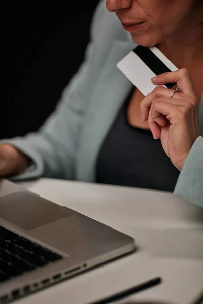 Giovane donna d'affari caucasica seduta nel suo ufficio e che utilizza la carta di credito per pagare l'abbonamento per il software con licenza . — Foto Stock