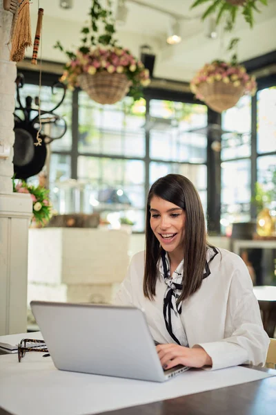 Young attractive caucasian restaurant manager sitting at table and using laptop for organizing business. — Stock Photo, Image
