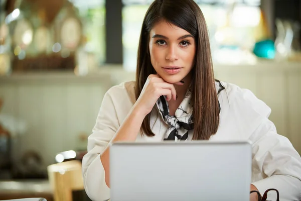 Charmante blanke zakenvrouw zittend in een café en poserend. Voor haar ligt een laptop.. — Stockfoto