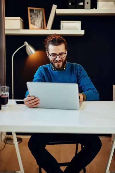 Красивий білий бізнесмен сидить у своєму сучасному офісі і використовує ноутбук для написання звіту . — стокове фото