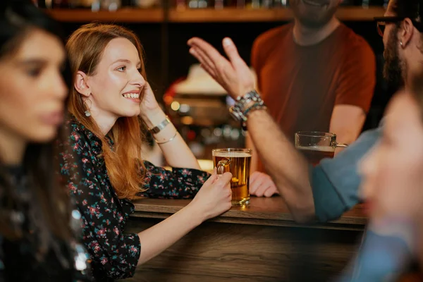 Group of friends drinking beer, chatting and having good time at pub. Night out.