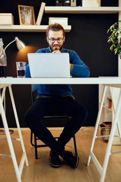 Knappe blanke bebaarde zakenman zit in zijn moderne kantoor en gebruikt laptop voor het schrijven van rapport. — Stockfoto