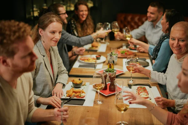 Group of friends sitting in retaurant and eating dinner. — Stock Photo, Image