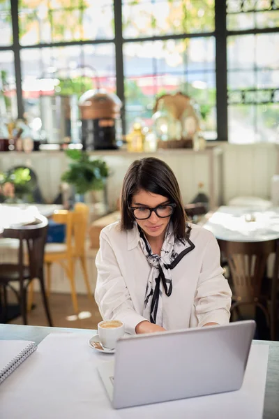 Gericht aantrekkelijke Kaukasische brunette met bril gekleed in shirt zitten in cafe en met behulp van laptop voor het werk. Bedrijfsconcept op afstand. Handen op het toetsenbord.bril gekleed in — Stockfoto