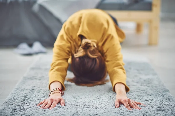 Брюнетка делает расширенную позу йоги для детей на ковре в спальне . — стоковое фото