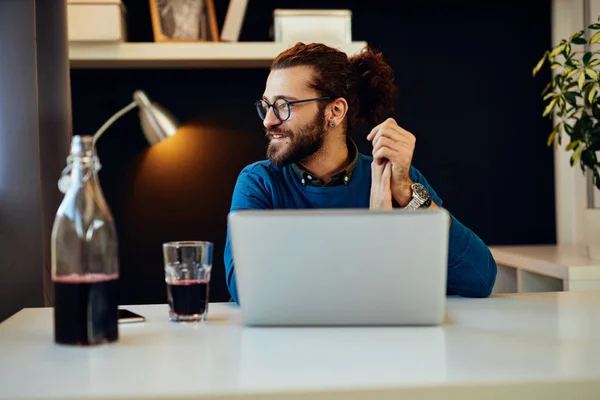 Guapo barbudo caucásico freelancer sentado en su oficina en casa y mirando a través de la ventana . — Foto de Stock