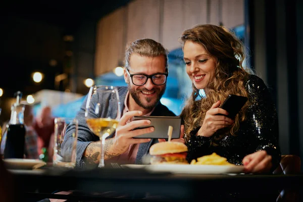 Mignon caucasien à la mode couple assis dans restaurant au dîner et prendre selfie . — Photo
