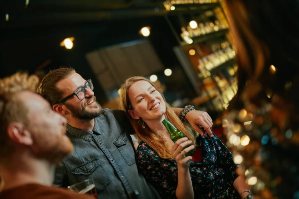 Un gruppo di amici che beve birra, chiacchiera e si diverte al pub. Notte fuori . — Foto Stock