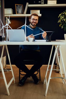 Yakışıklı sakallı beyaz girişimci ofisinde oturuyor ve önemli bir proje üzerinde çalışıyor. Sürdürülebilir konsept.