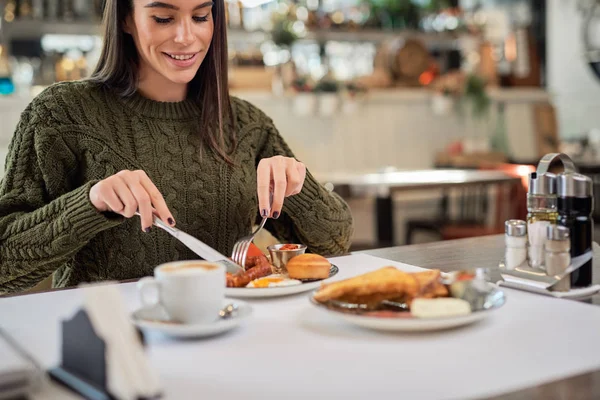 Atrakcyjna brunetka siedzi rano w restauracji i je śniadanie. — Zdjęcie stockowe