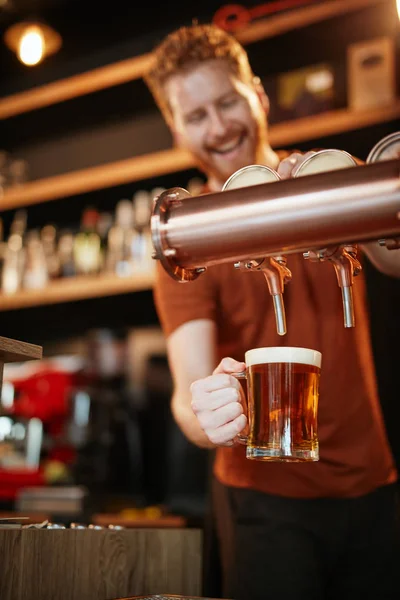 Schöner kaukasischer Barmann, der Bier einschenkt, während er in der Kneipe steht. Selektiver Fokus auf die Hand. — Stockfoto
