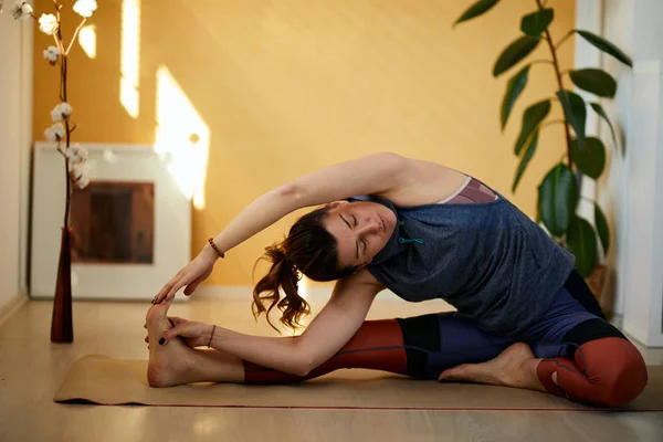 Atraktivní flexibilní bělošská brunetka na jógu v otočené hlavě k józe. Interiér domu, ranní čas. — Stock fotografie