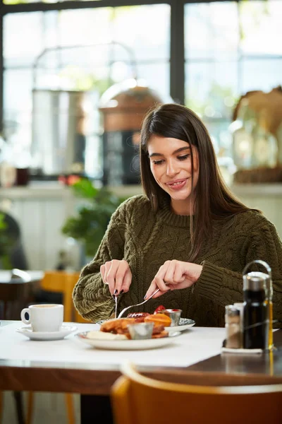 Morena atraente sentada no restaurante de manhã e tomando café da manhã . — Fotografia de Stock