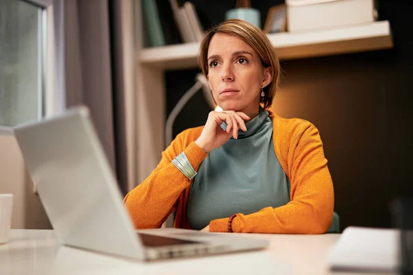 Kırklı yaşlardaki düşünceli iş kadını ofisinde oturmuş, çenesine sarılıp soruna çözüm arıyor.. — Stok fotoğraf