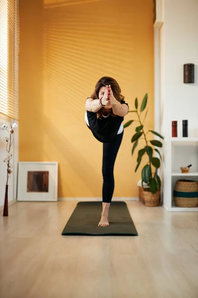 Brünette mittleren Alters steht in Warrior III Yoga-Pose. — Stockfoto