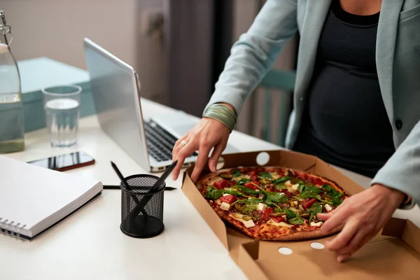 Cutout foto van Kaukasische zwangere zakenvrouw in de veertig en gekleed in pak op kantoor en pizza eten voor de lunch. — Stockfoto
