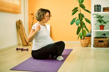 Sabahları orta yaşlı hamile bir kadın mindere oturup meditasyon yapıyor. İç mimari.