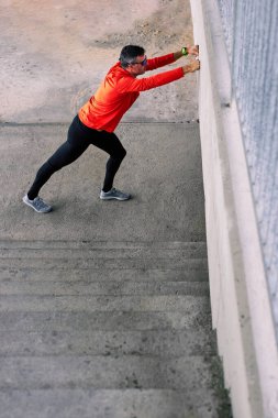 Orta yaşlı Kafkas sporcusu koşmadan önce açık havada excises ısıtıyor..