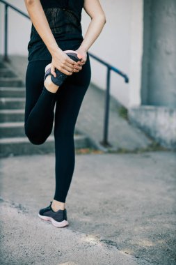 Genç ve çekici bir kadın koşmadan önce bacağını esnetiyor..