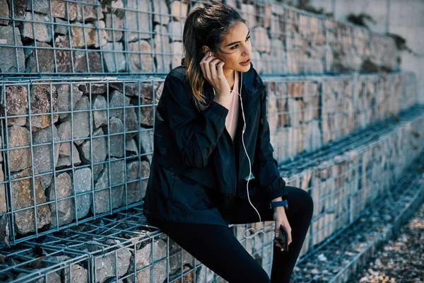 Joven Morena Atractiva Descansando Después Correr Mientras Pone Auriculares Para — Foto de Stock