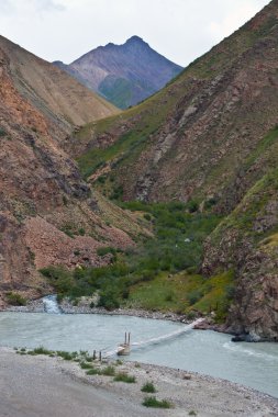 Tien Shan dağlarında nehri geçip yaya köprüsü