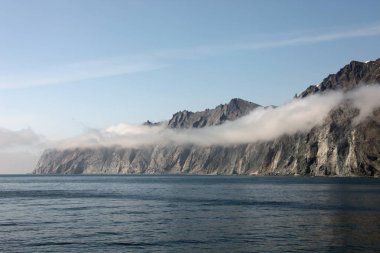 Kayalık sabah sis Okhotsk deniz kıyısında.