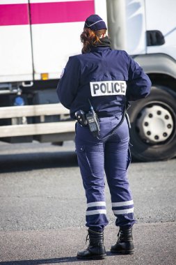 Paris'te bir sokakta polis kamu düzenini kontrol eder. Tam teçhizatlı bir kadın polis trafik yönetimini izliyor. Teçhizat, telsiz, kelepçe, kanun adamının silahları.
