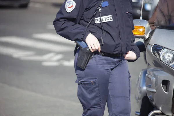 A female police officer controls traffic in the city. A woman in a police uniform with weapons and communications equipment at a vehicle on the road. France